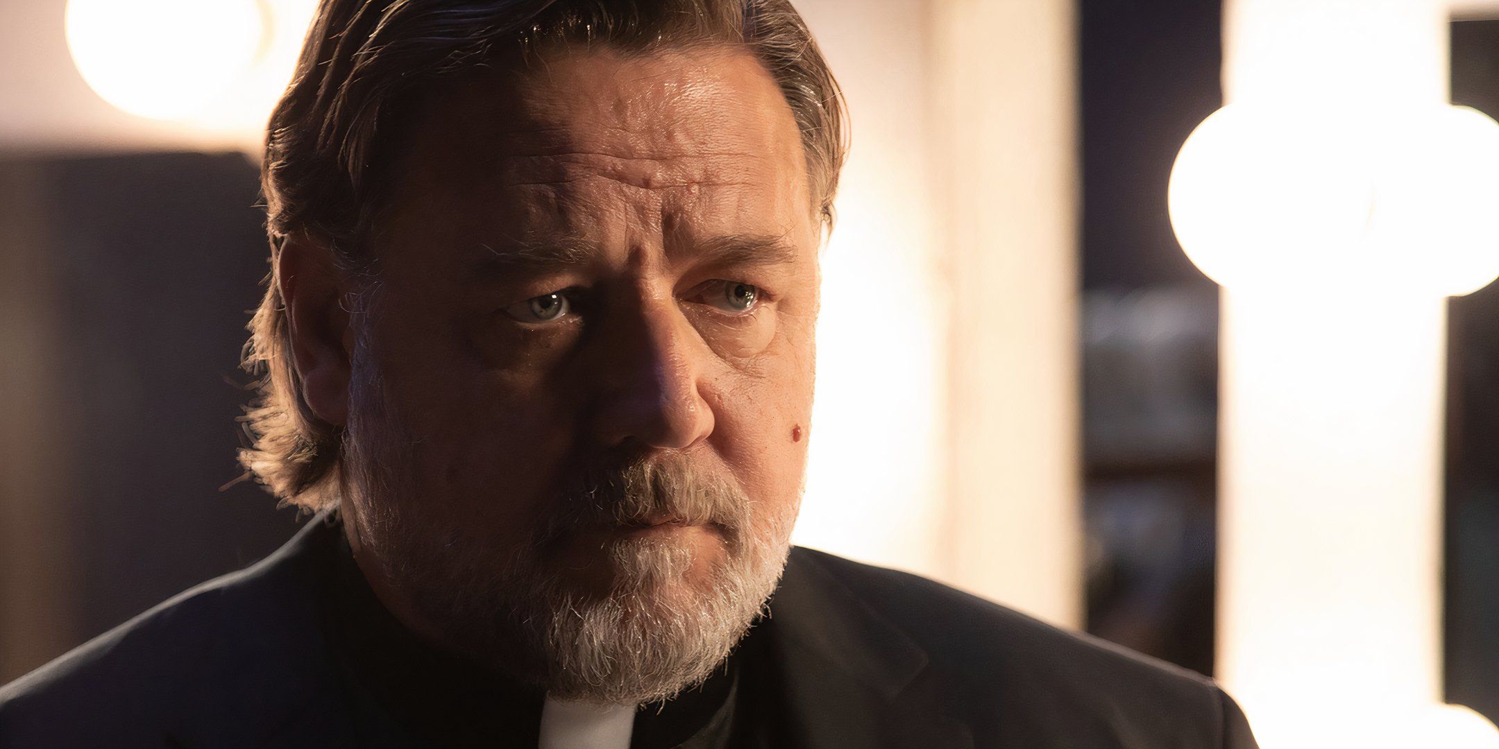 Russell Crowe as Anthony in his priest costume looking in the mirror in The Exorcism