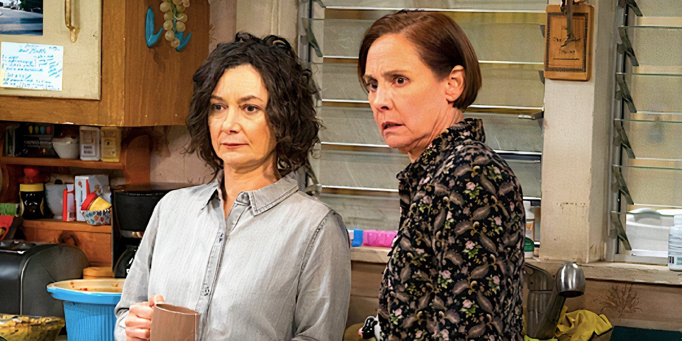 Sara Gilbert's Darlene and Laurie Metcalf's Jackie stare at something offscreen while standing in the kitchen in The Conners