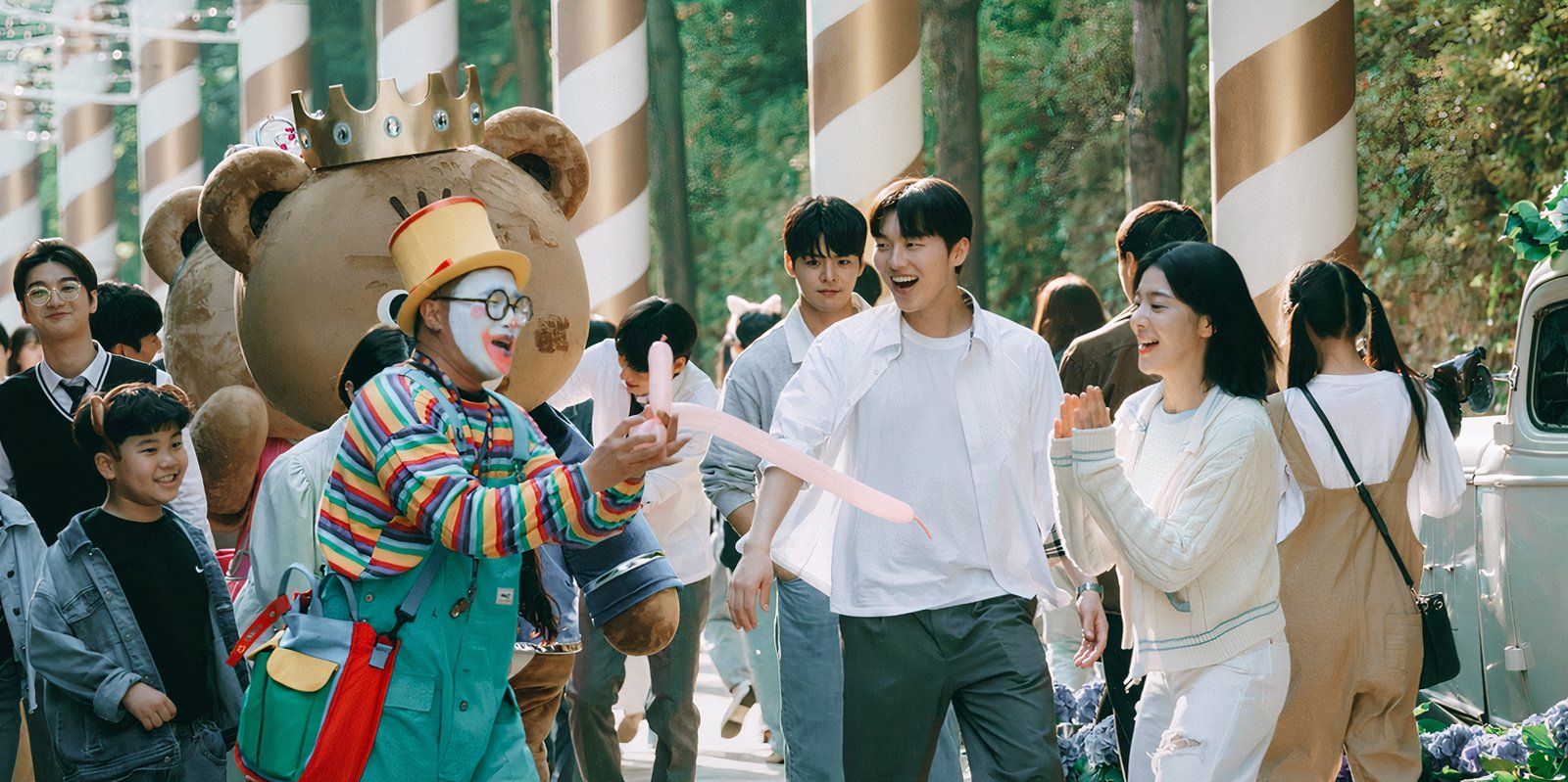 The cast of Twinkling Watermelon clap as they watch a clown blow up a balloon.