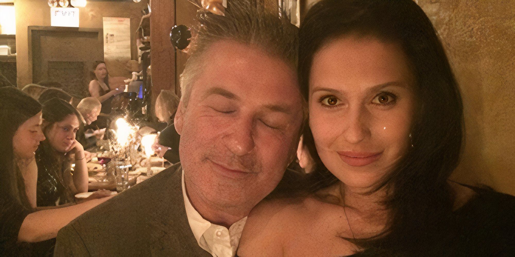 The Baldwins Alec Baldwin e Hilaria Baldwin abraçados com uma mesa de jantar lotada ao fundo