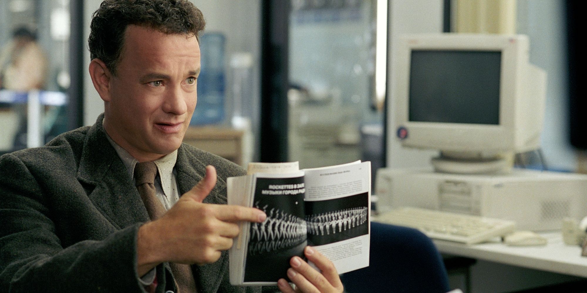 Tom Hanks in an office pointing to a picture in The Terminal