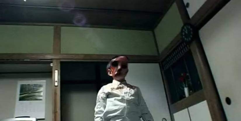 Paranormal visions Noroi The Curse, a person with their face distorted stands in a room looking down at the viewer