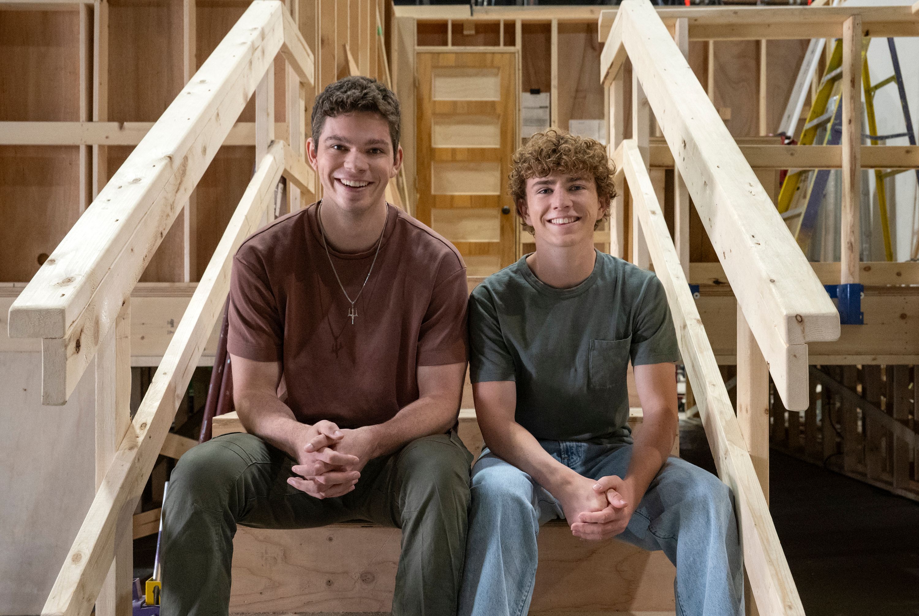 Daniel Diemer e Walker Scobell sentados lado a lado em uma escada no set de Percy Jackson