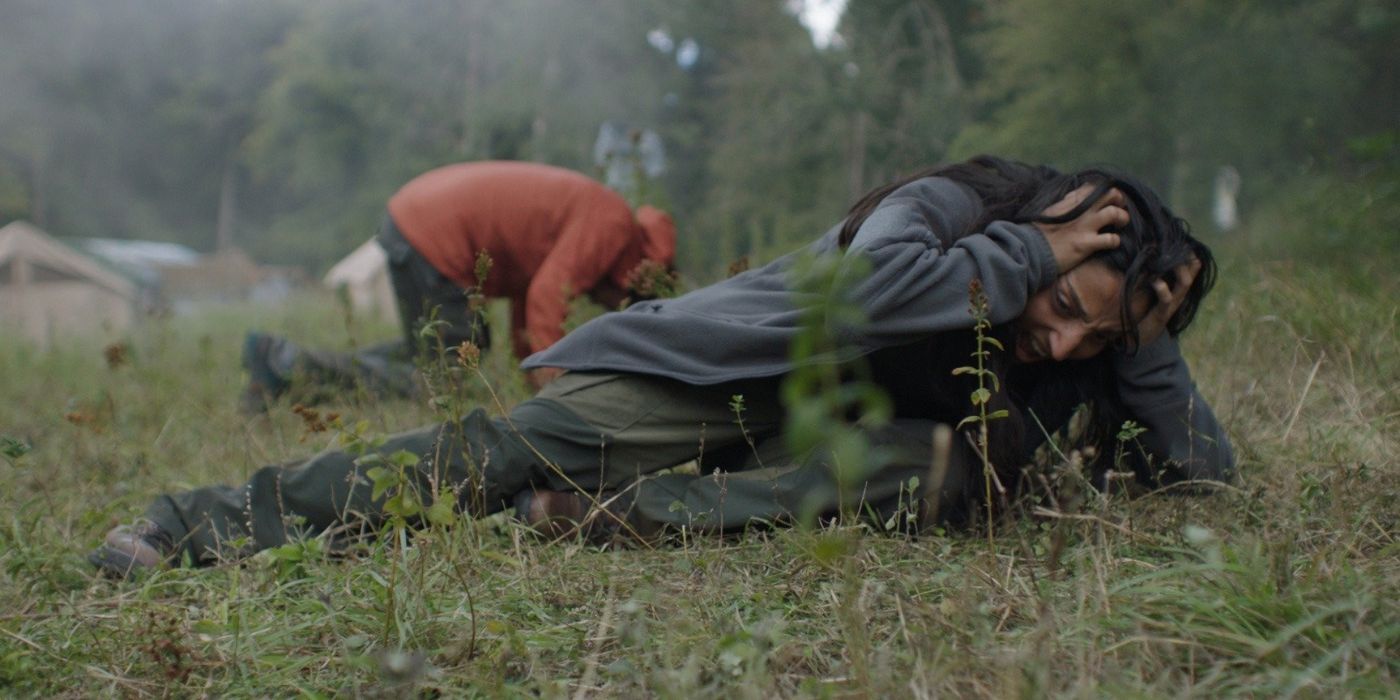 airborne violence in in the earth two people lie on the grass with their hands against their heads crying out in pain