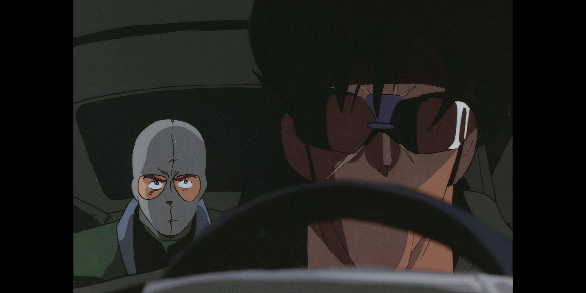 Bean Bandit, wearing sunglasses sits in the front seat of his car, while transporting a masked robber in the backseat.