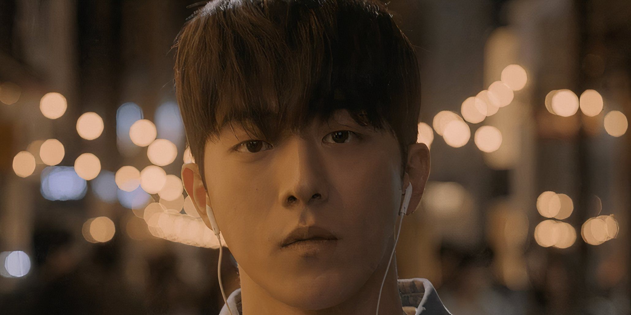 A young man walks down the street with earbuds in during the K drama Vigilante