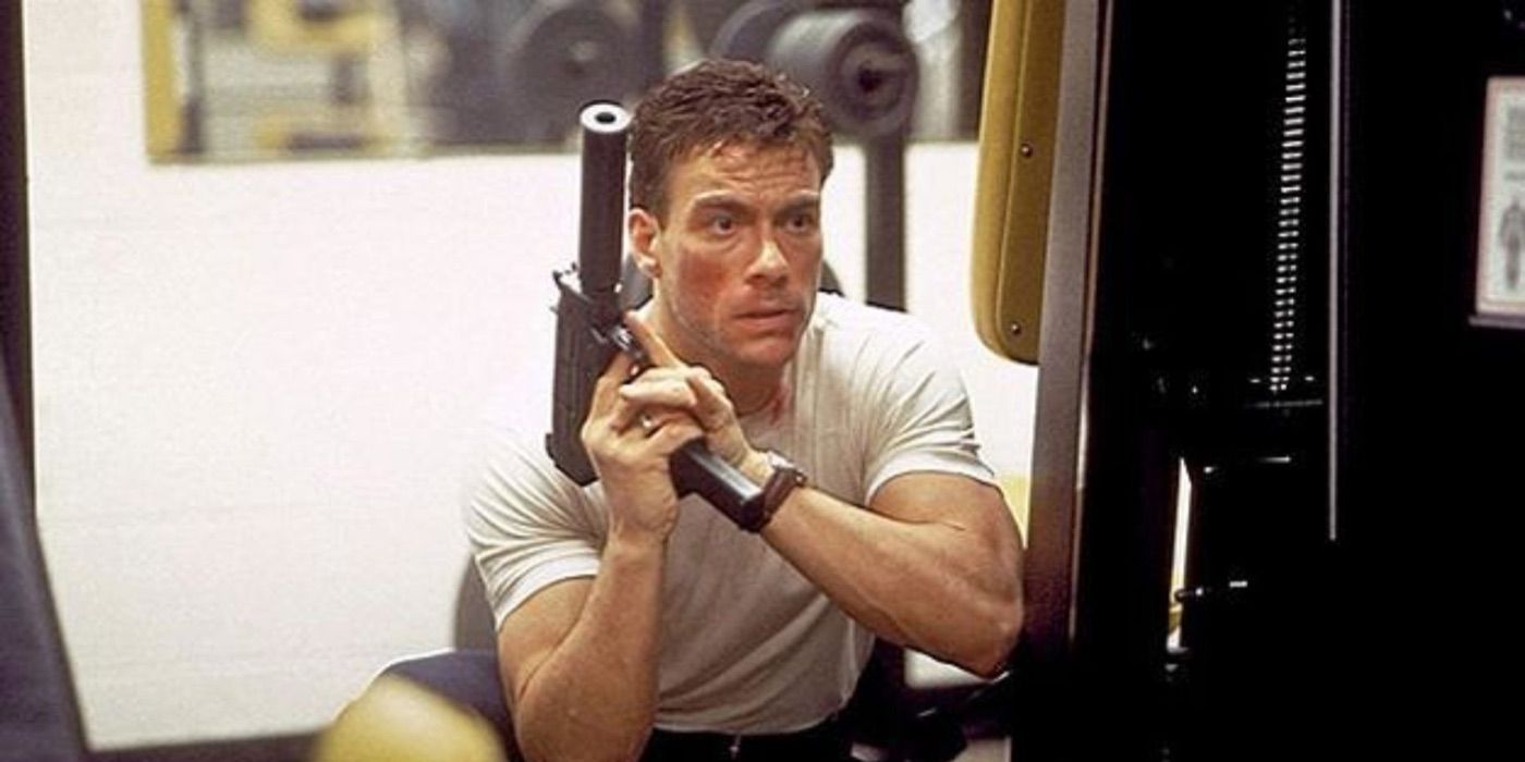 Jean-Claude holding a machine gun and taking cover in Sudden Death (1995)