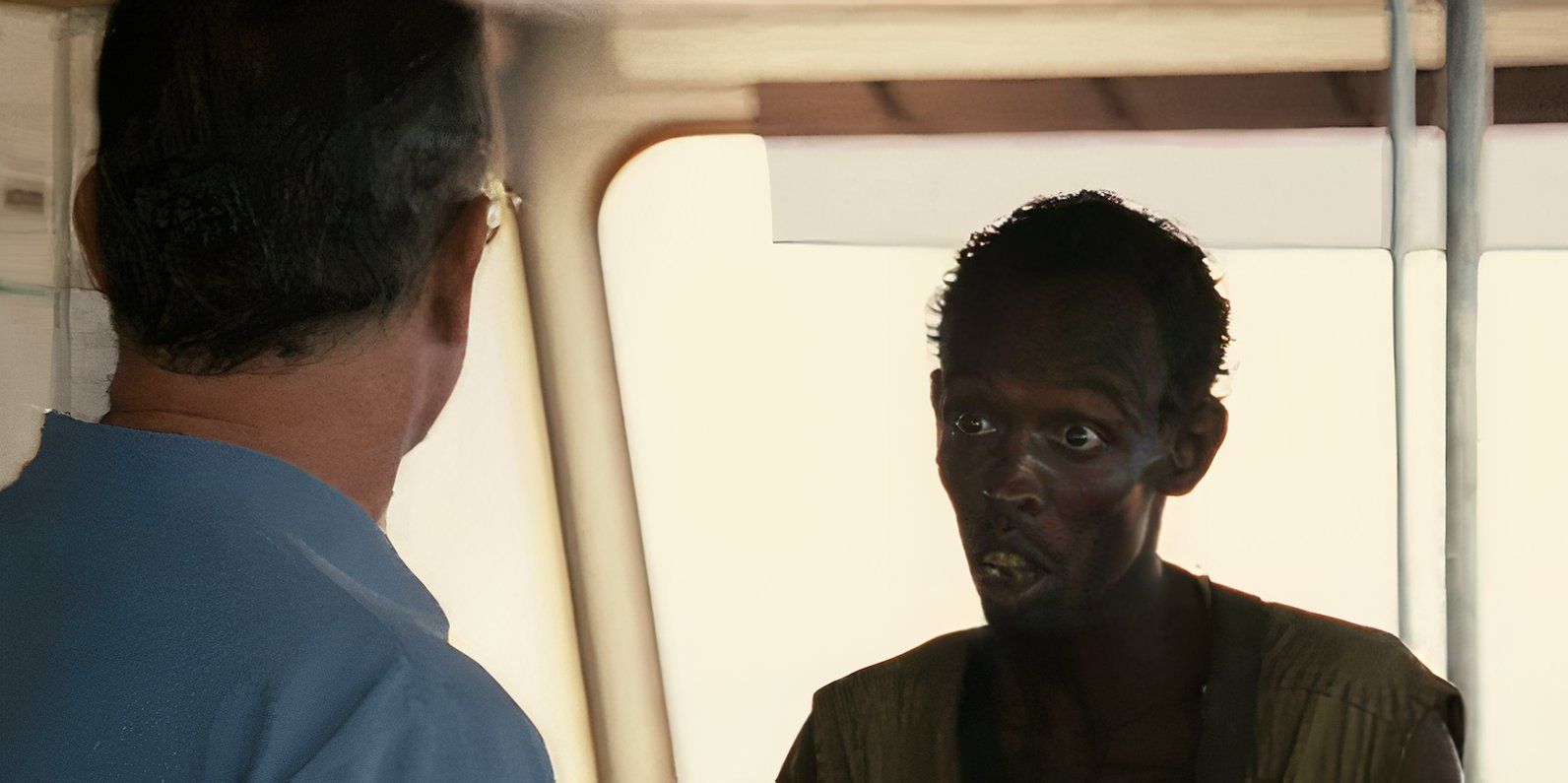 Barkhad Abdi como Abduwali Muse interrogando o Capitão Phillips (Tom Hanks) em Capitão Phillips