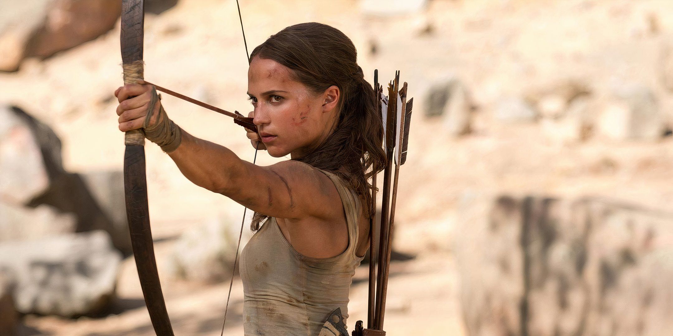 Alicia Vikander as Lara Croft aims a bow and arrow in Tomb Raider.