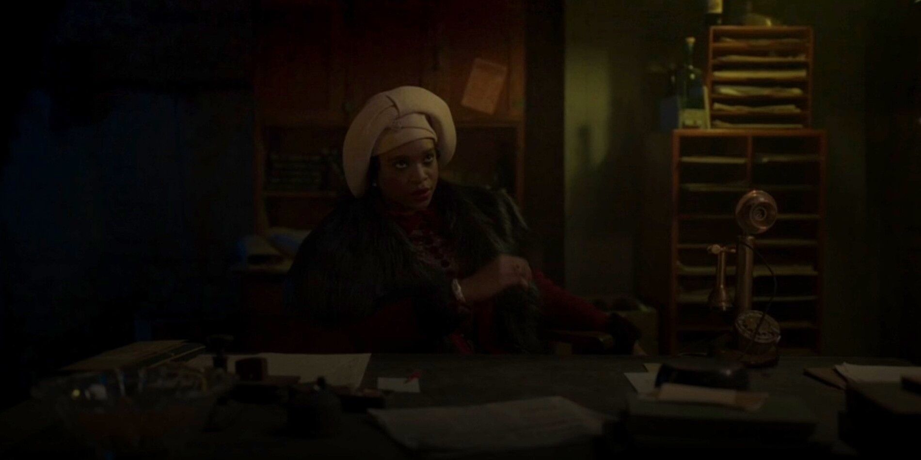 Andrea Solonge As Madame Queenie Sitting At Desk In Time Bandits 2024.jpg