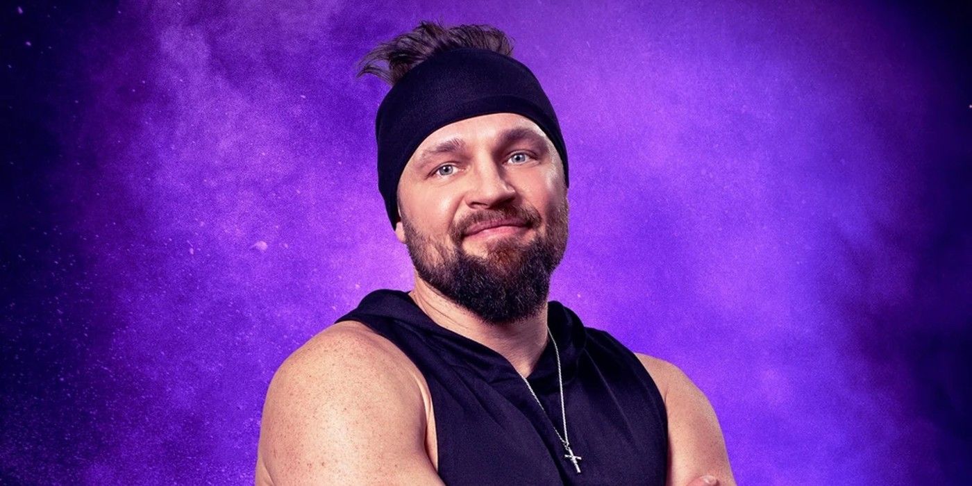 Derrick Kosinski from The Challenge Season 40 smiling in a headband with his arms crossed in front of a purple background.