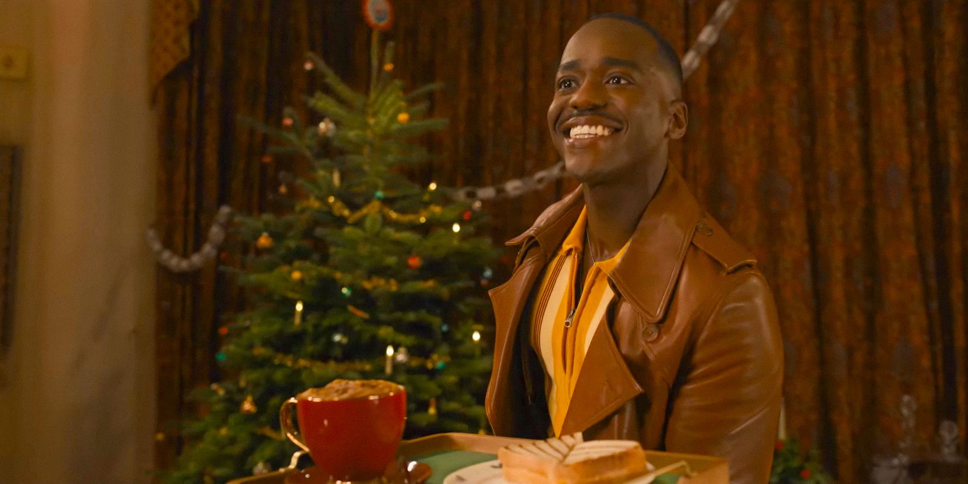 In a room decorated with a Christmas tree, The Doctor (Ncuti Gatwa) offering a ham and cheese toastie and a pumpkin latte in a Doctor Who Christmas Special Clip (2024)