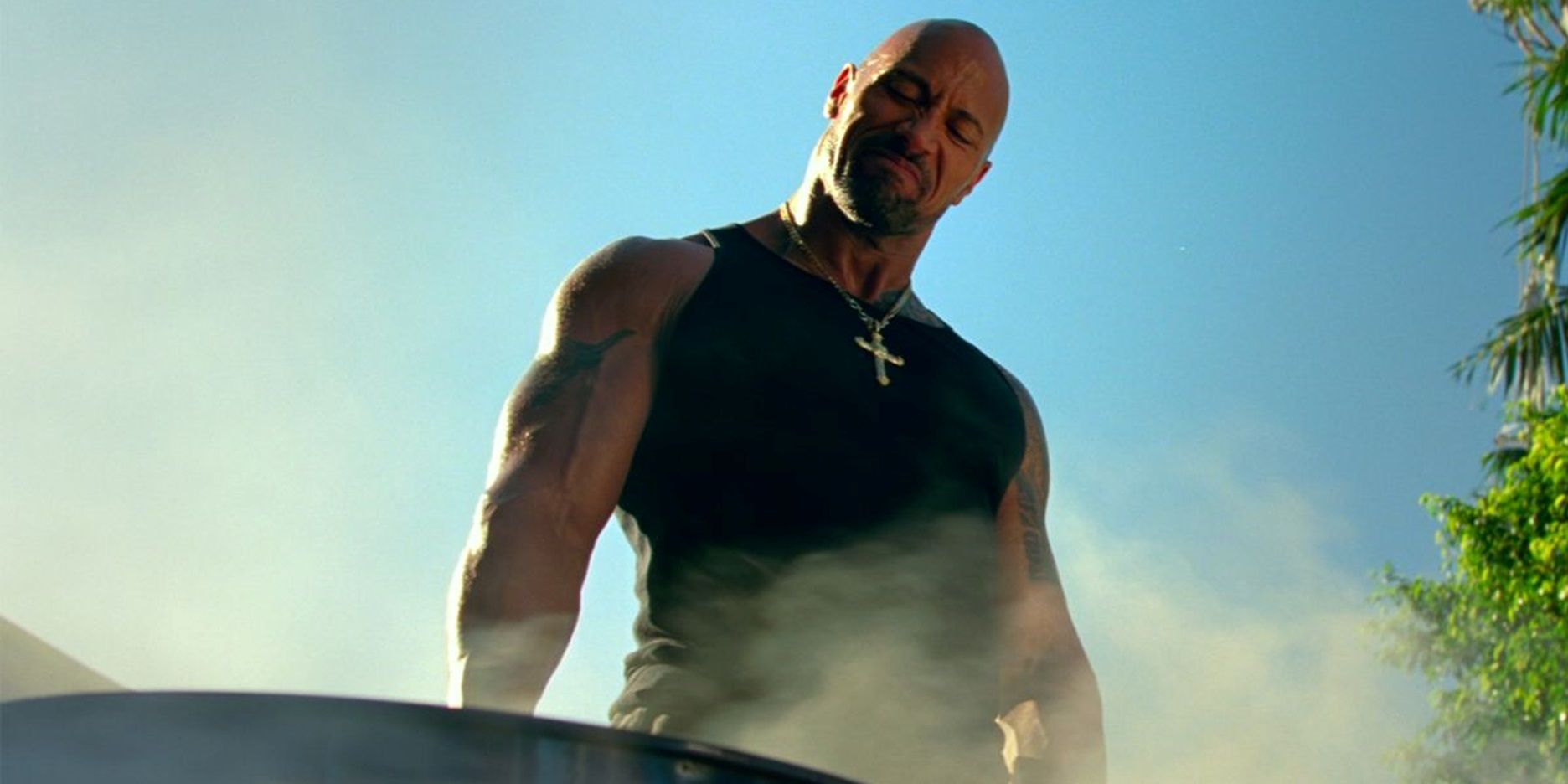 Dwayne Johnson standing by a grill in Pain and Gain