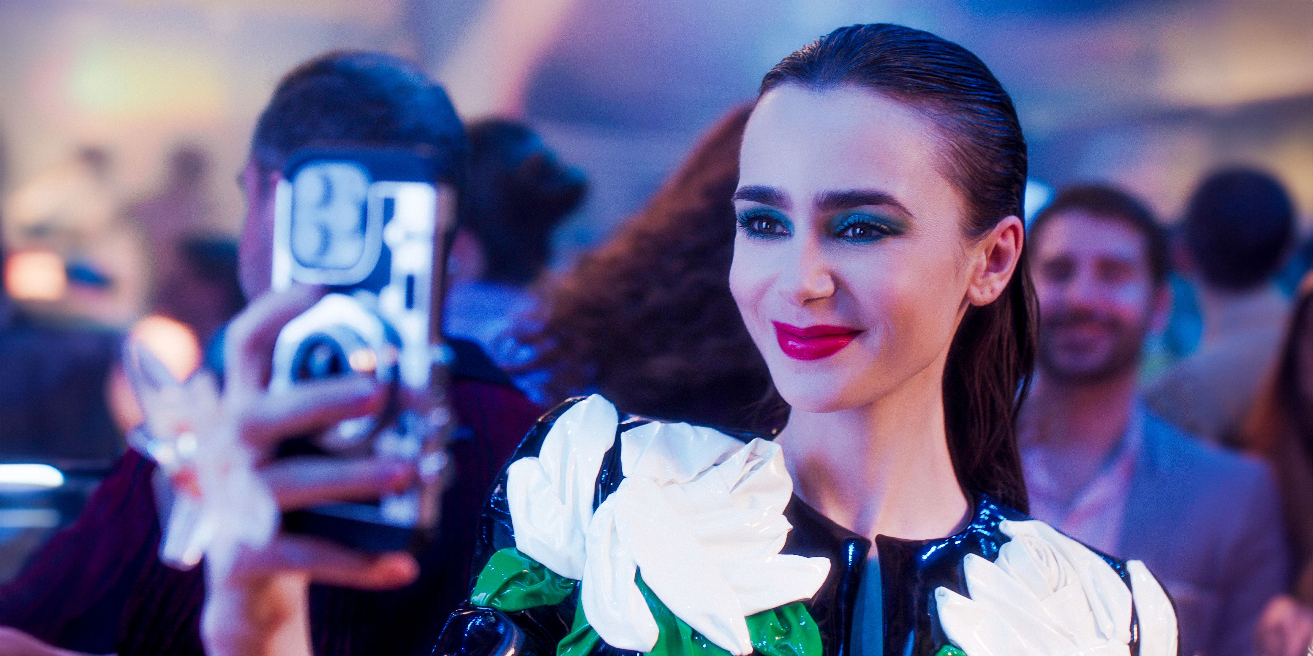 Emily (Lily Collins) taking photos with her phone at a party in Emily in Paris season 4