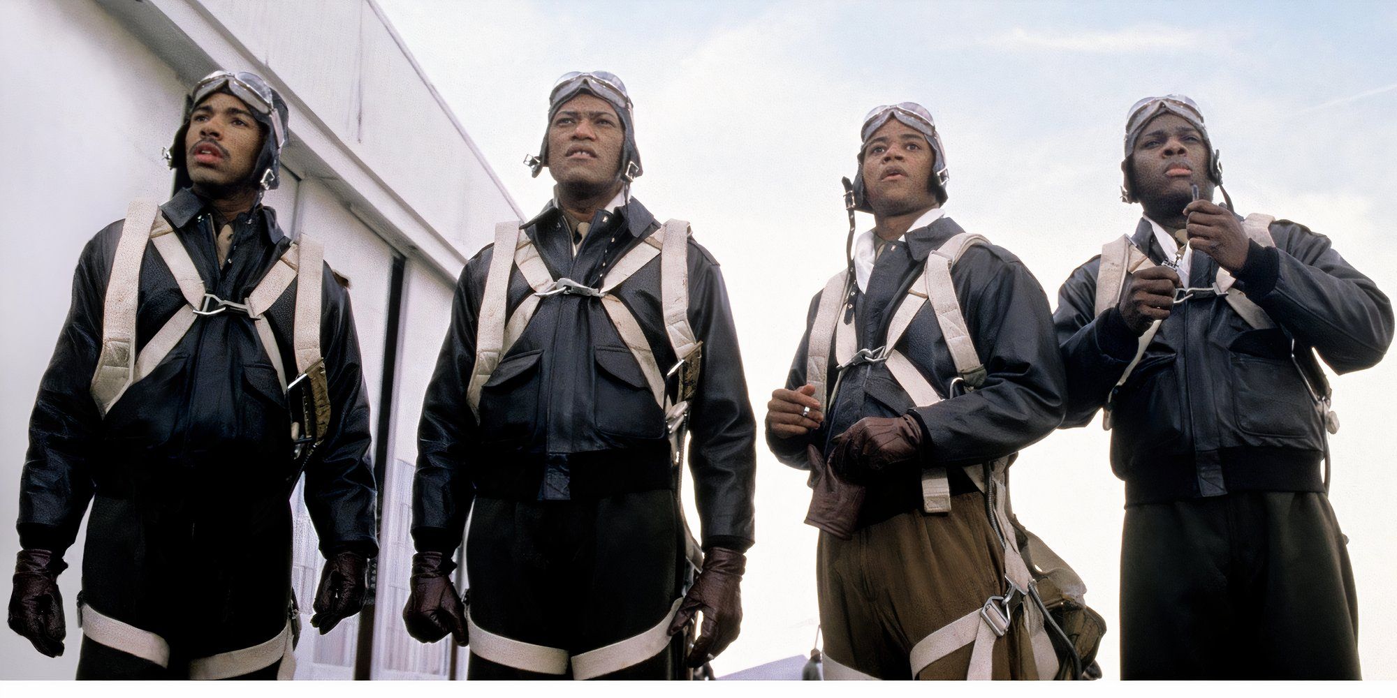Quatro membros dos Tuskegee Airmen em pé juntos com o céu atrás deles