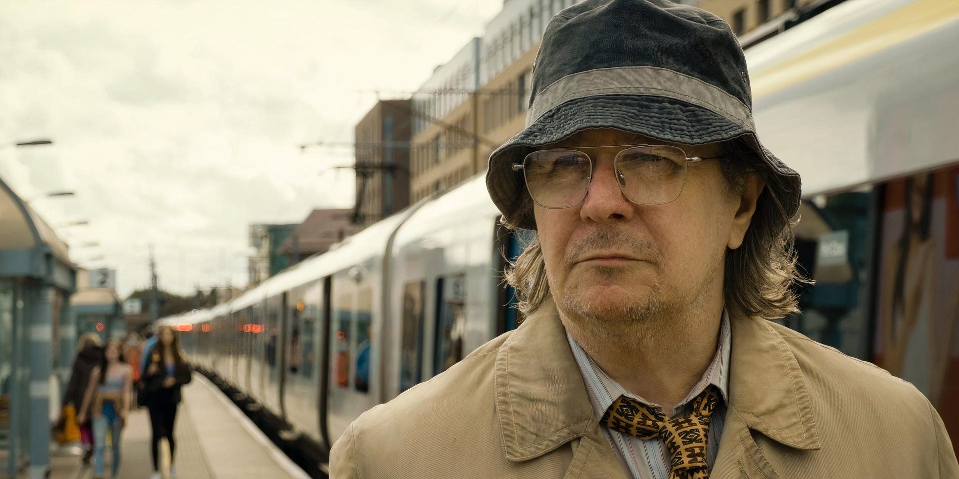 Gary Oldman como Jackson Lamb mira fijamente una estación de tren al aire libre en Slow Hoses