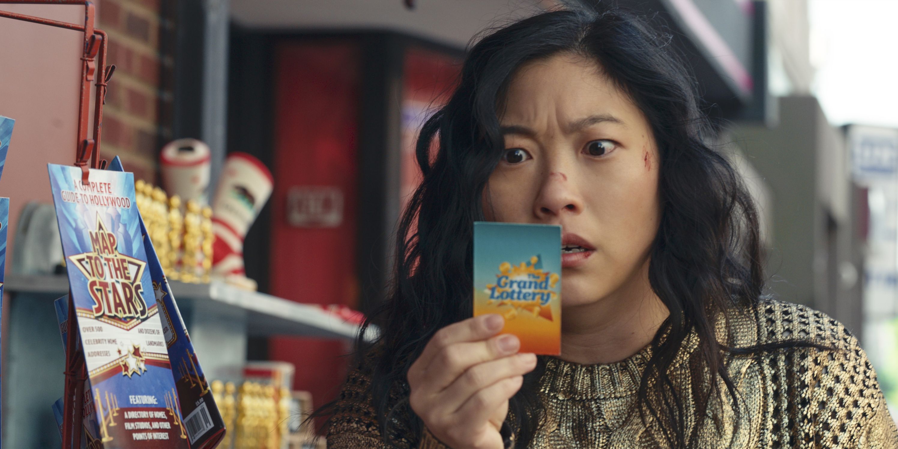 Awkwafina como Katie olhando para um bilhete em choque no Jackpot.