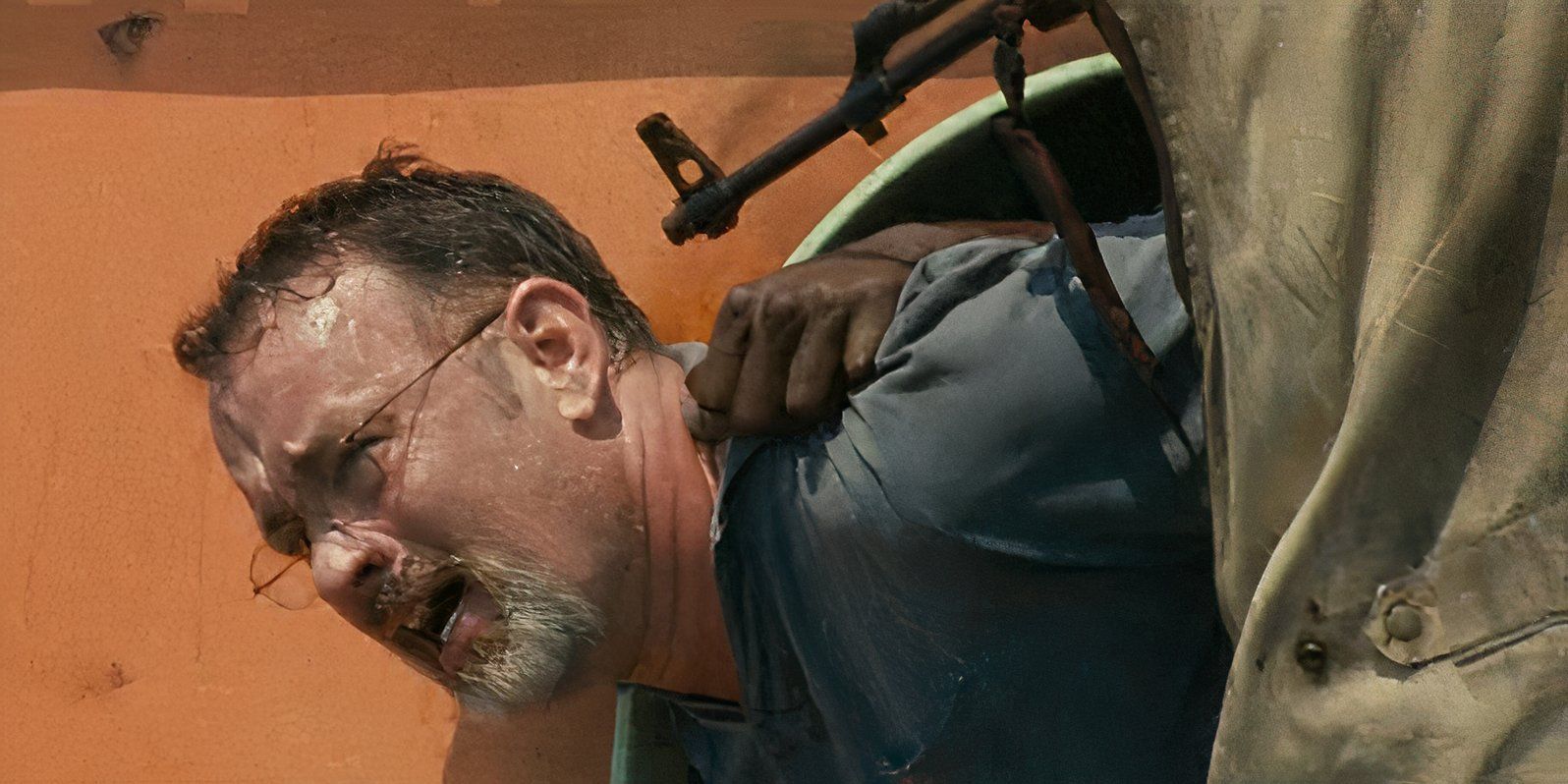 Tom Hanks as Richard Phillips with a gun to his head in a lifeboat in Captain Phillips