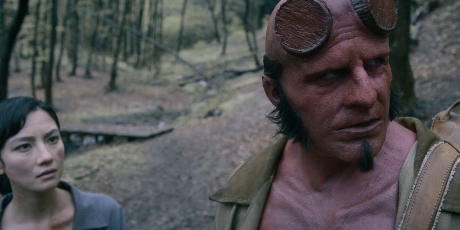 Jack Kesy como Hellboy e outro personagem olhando para longe, confuso, em Hellboy The Crooked Man