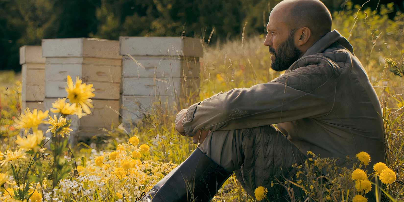 Jason Statham's Adam Clay sitting in a field of flowers in The Beekeeper