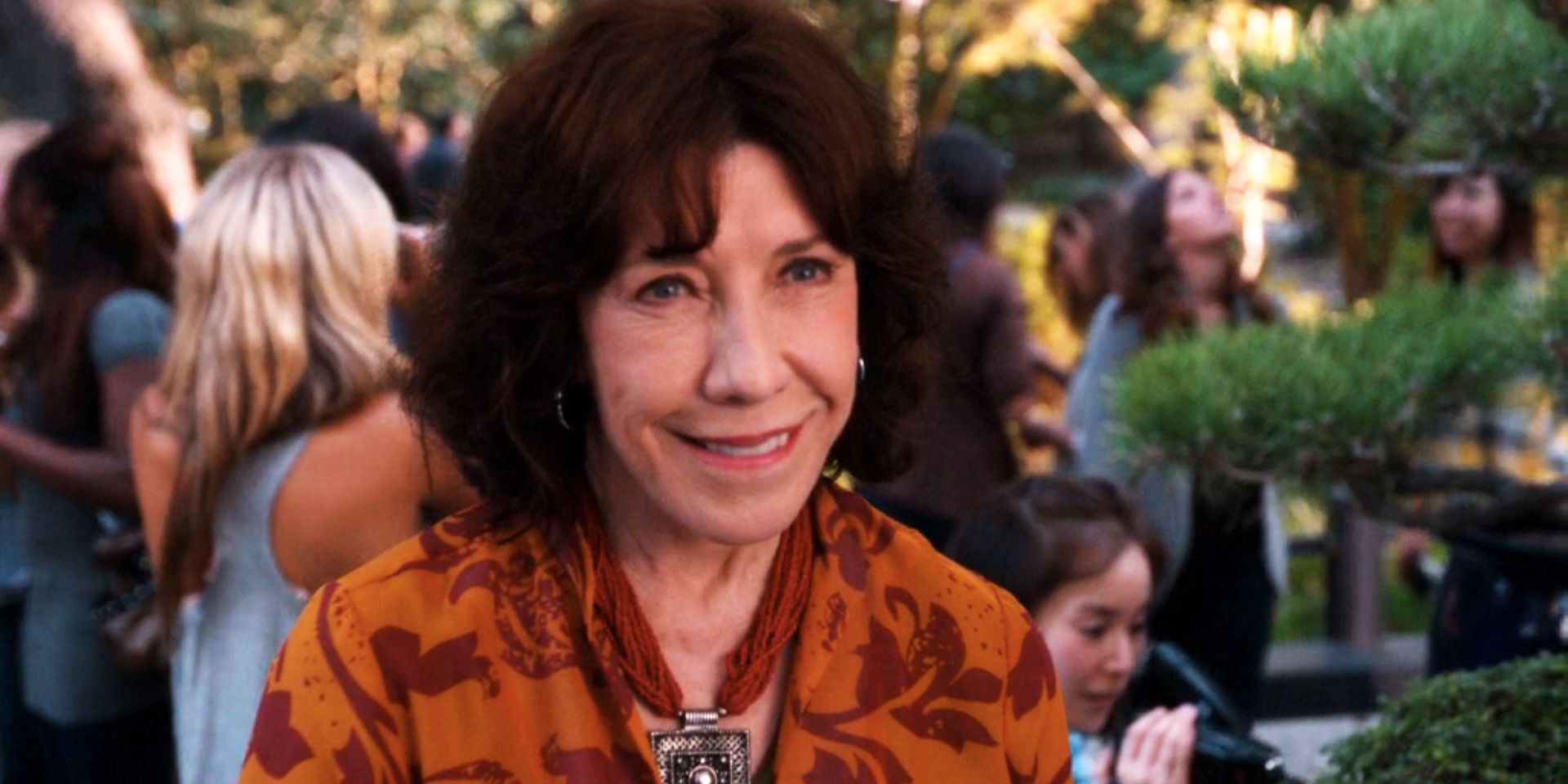 Lily Tomlin standing in a garden and smiling in NCIS