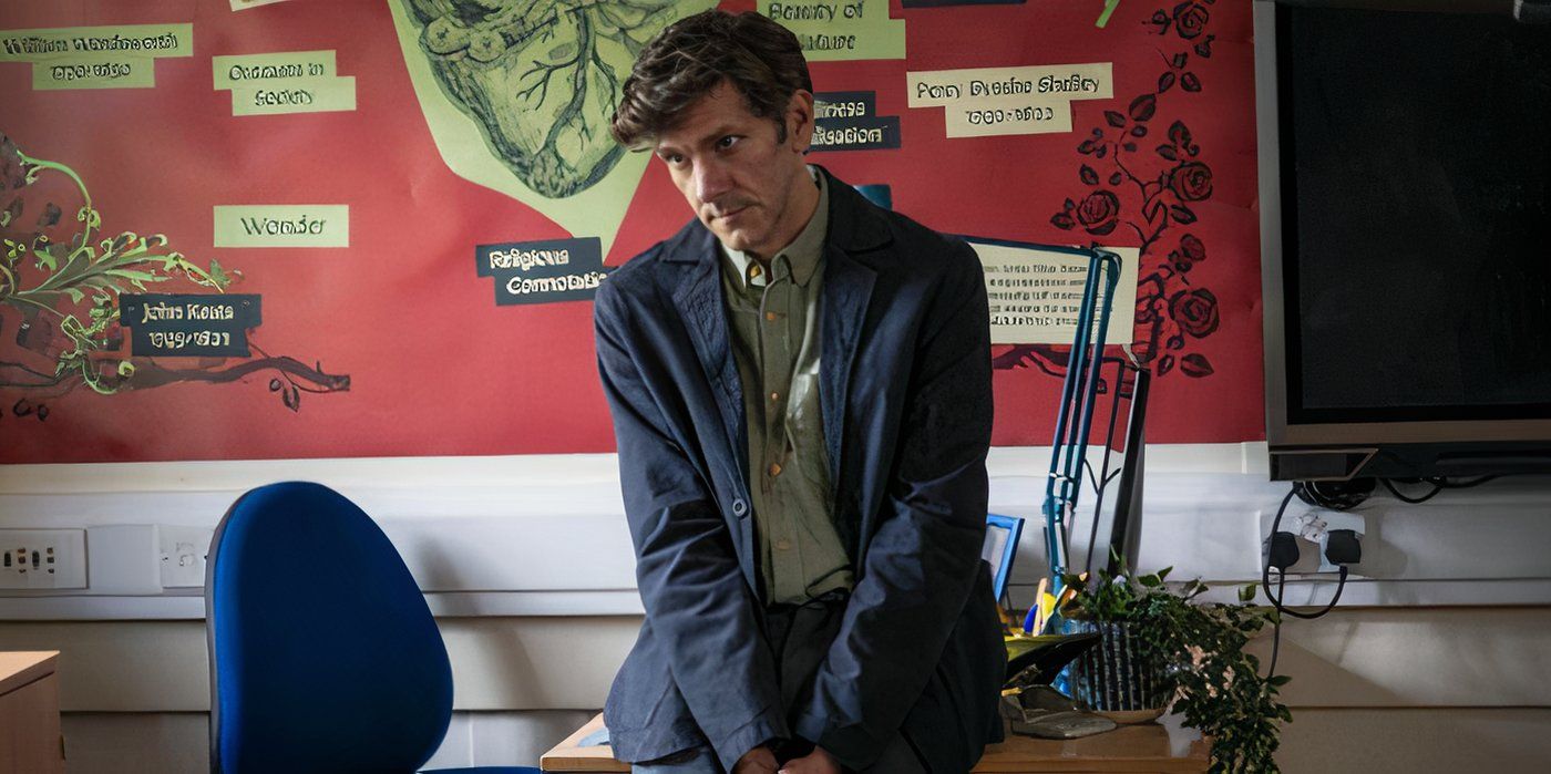 Mathew Baynton como Eliot Ward em A Good Girl's Guide to Murder sentado em uma sala de aula em frente a um quadro