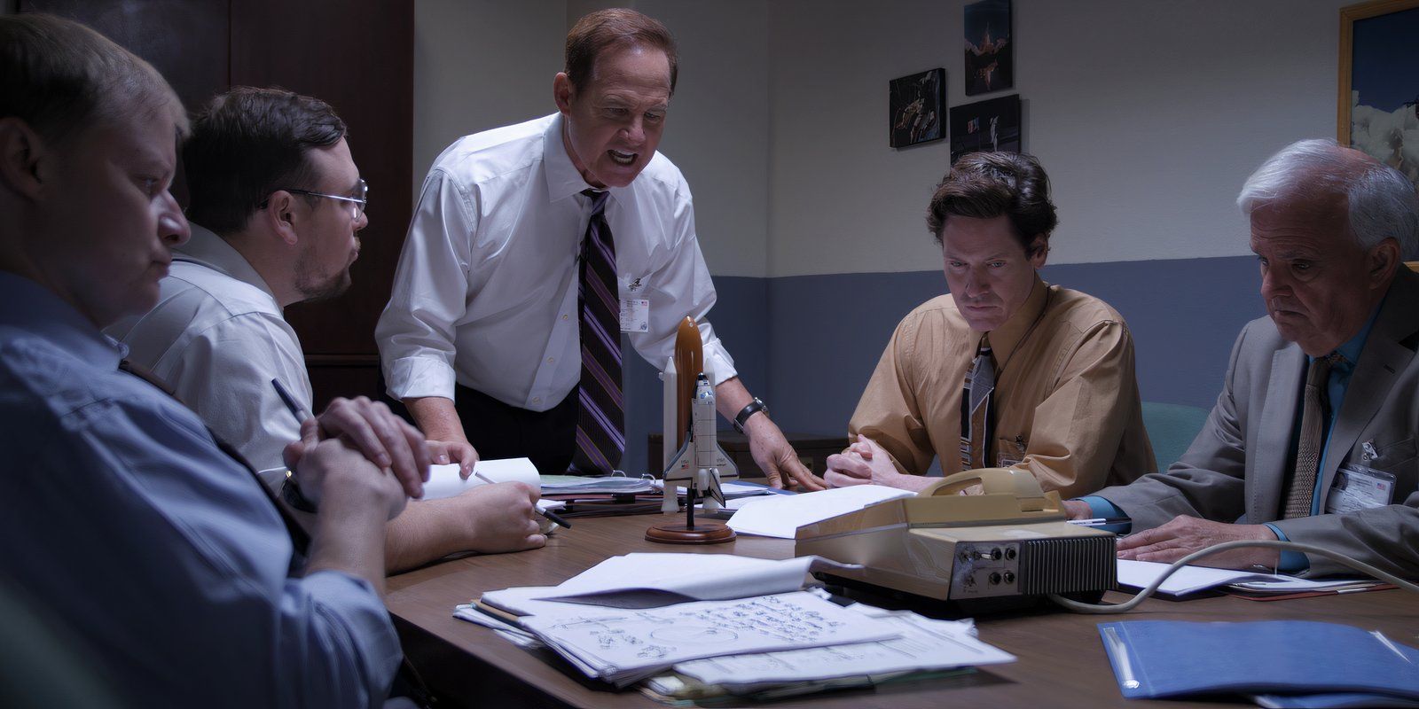 NASA Employees sit at a table with a model of the Challenger space shuttle in The Challenger Disaster