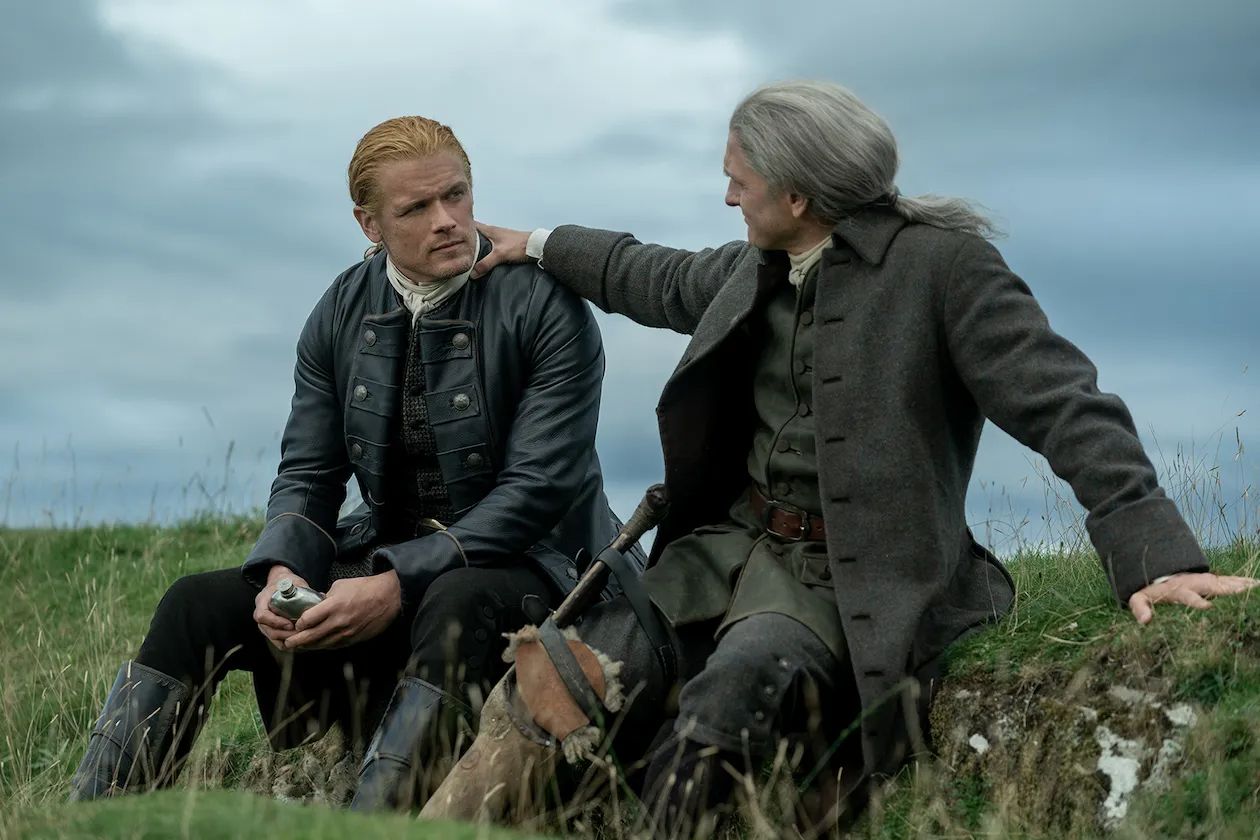 Jamie and Ian sitting in a field in Outlander season 7 part 2