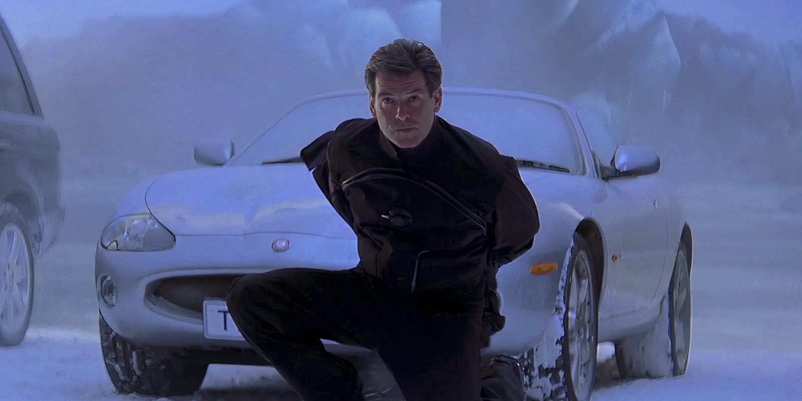 Pierce Brosnan takes off his coat in front of an Aston Martin in “Die Another Day”