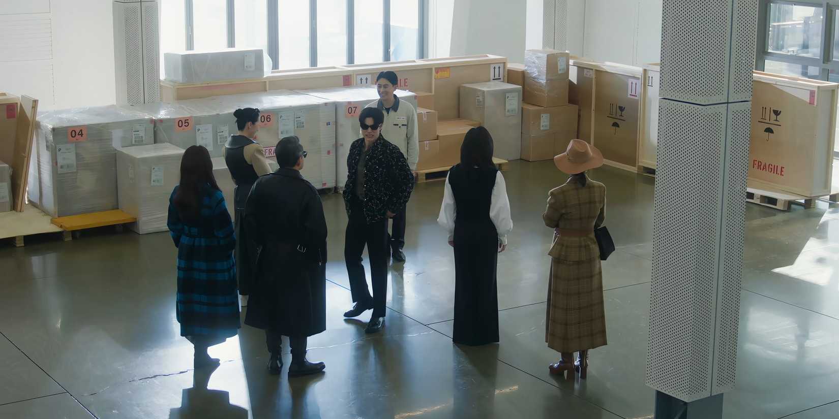 Queen of Tears' Hong Soo-cheol grimaces and turns away from a staff member while the rest of his family face the other way.