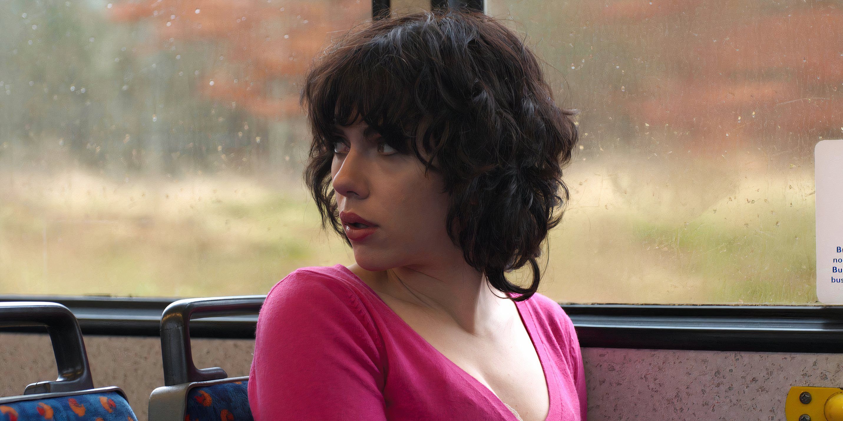 Laura (Scarlett Johansson) sitting on a bus looking back in Under the Skin