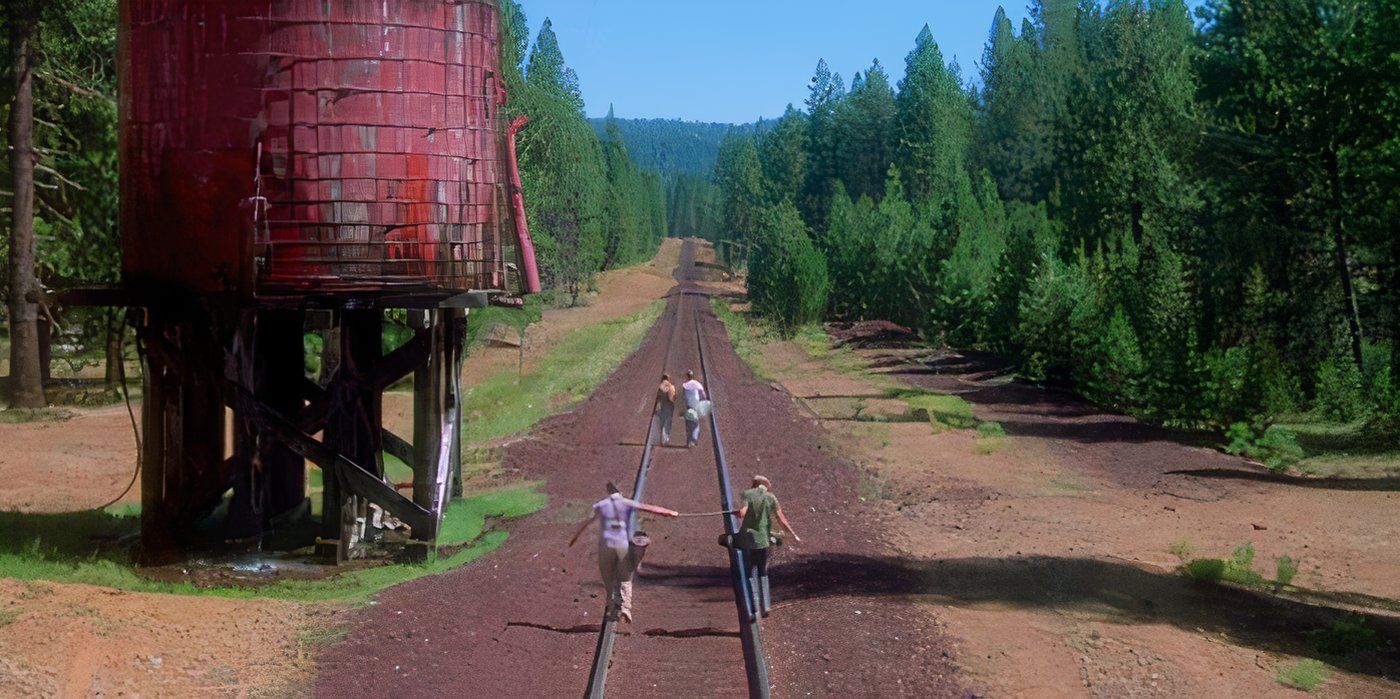 Teddy (Corey Feldman) and Vern (Jerry O'Connell) walking down a dirt road train track with Gordie (Wil Wheaton) and Chris (River Phoenix) up ahead in Stand By Me