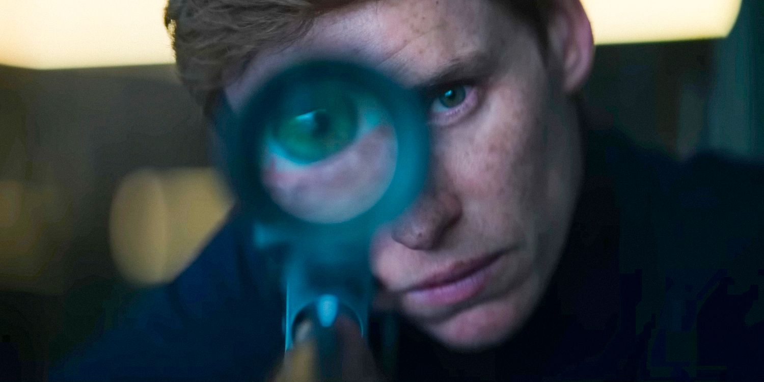 Chacal (Eddie Redmayne) olhando pela mira de um rifle em O Dia do Chacal