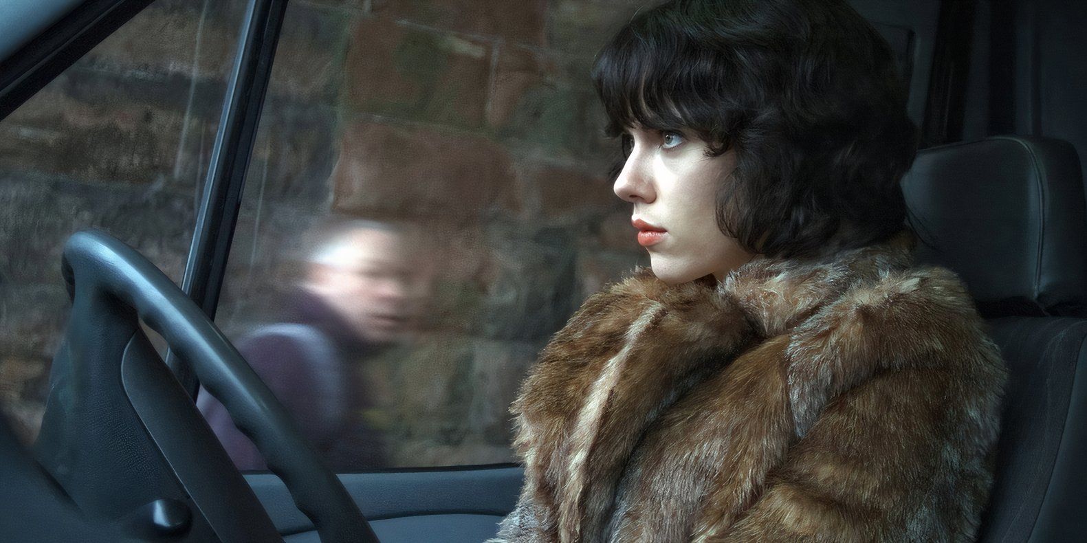 Scarlett Johansson sentada em um carro em Under the Skin