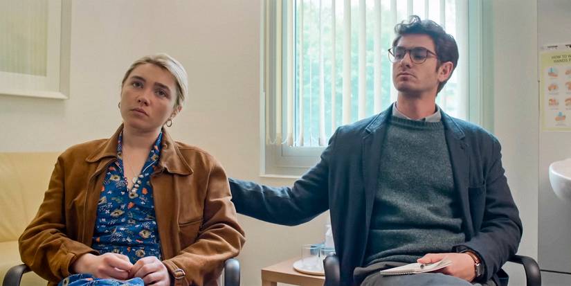 In a doctor's office, Tobias (Andrew Garfield) rubs Almut's (Florence Pugh) back to comfort her in We Live in Time