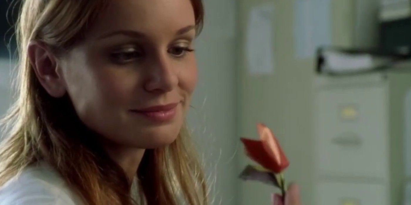 Sara smiles while holding an origami flower in Prison Break 