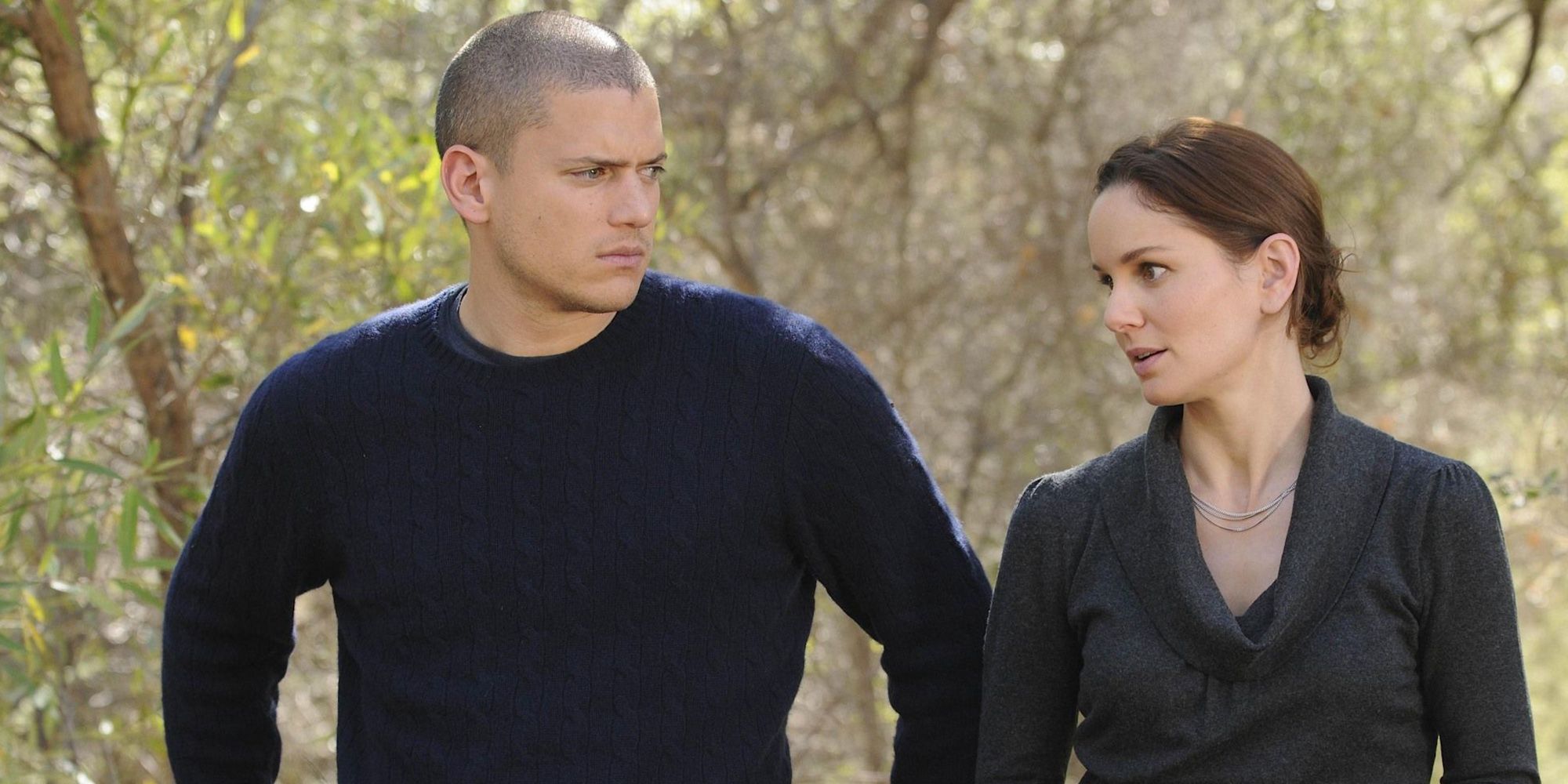 Michael and Sara standing next to each other by the woods in Prison Break