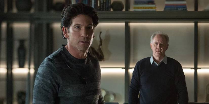 Jon Bernthal and John Lithgow look at something in the distance, surprised.