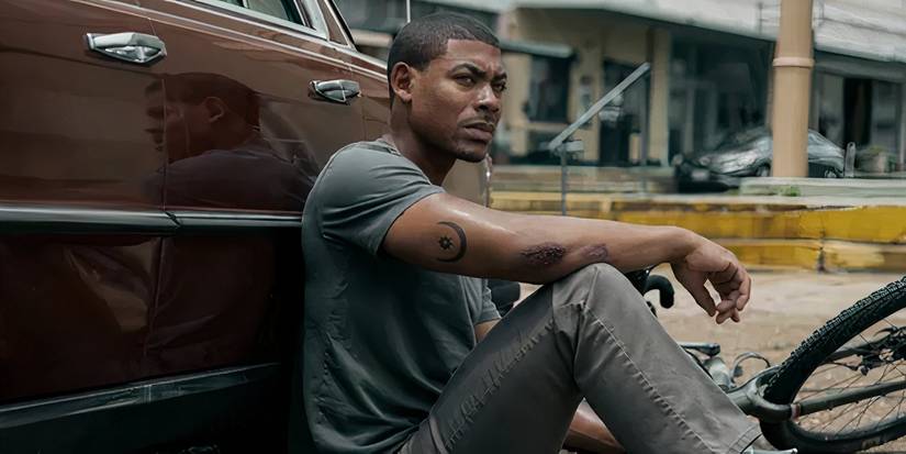 Aaron Pierre as Terry Richmond sitting against a car in Rebel Ridge