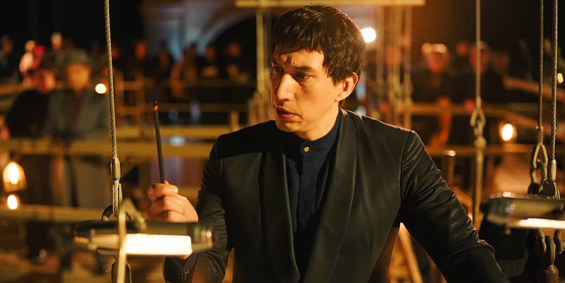 Adam Driver em um pódio contemplando um lápis em Megalopolis