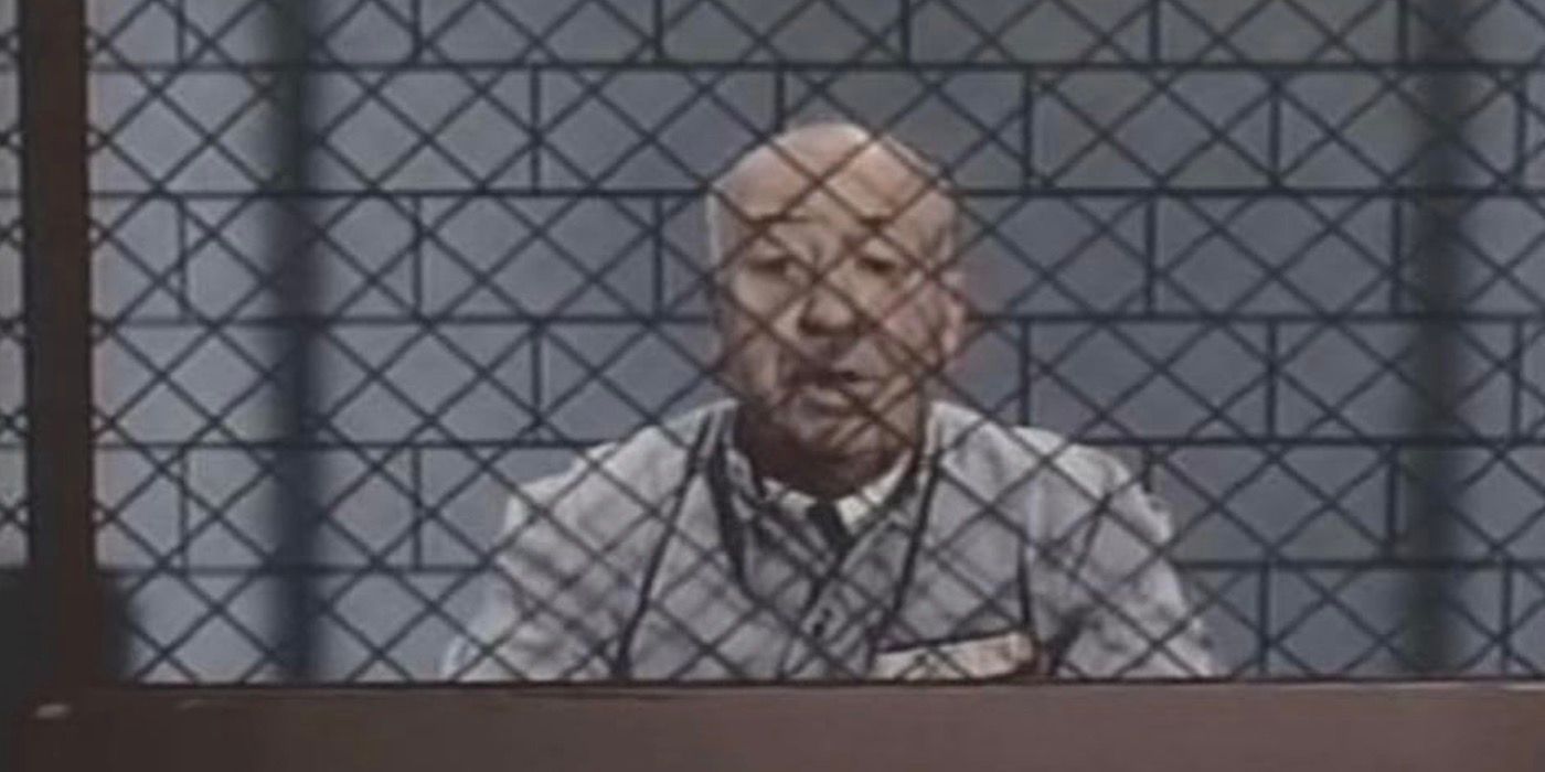 Alfred Hitchcock sits behind a wired barrier in The New Alfred Hitchcock Presents.