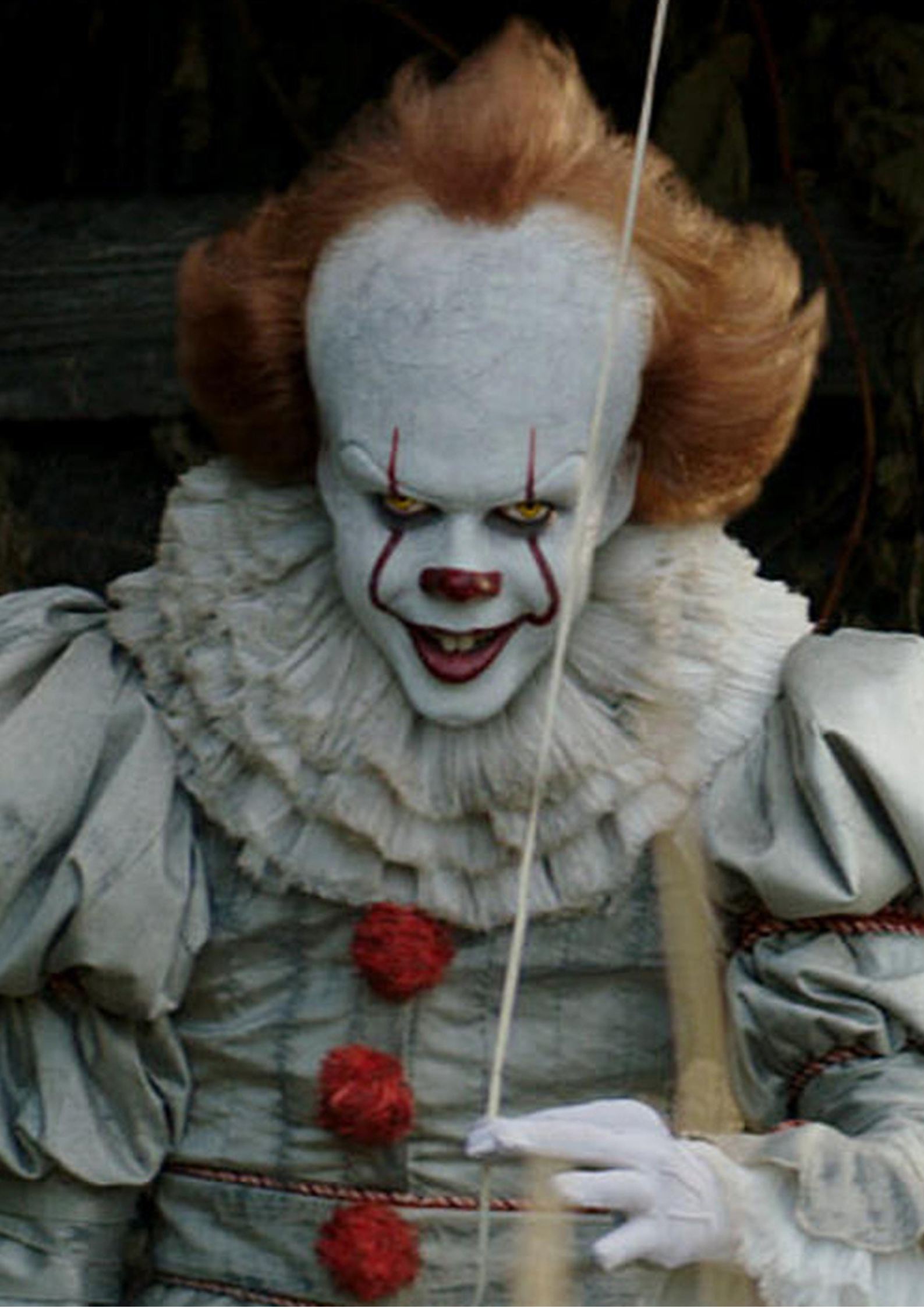 Bill Skarsgård as Pennywise holding a balloon string in It (2017)