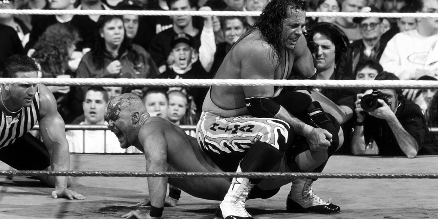 Bret Hart locks in the sharpshooter on Stone Cold Steve Austin as Ken Shamrock looks on at WWE WrestleMania 13