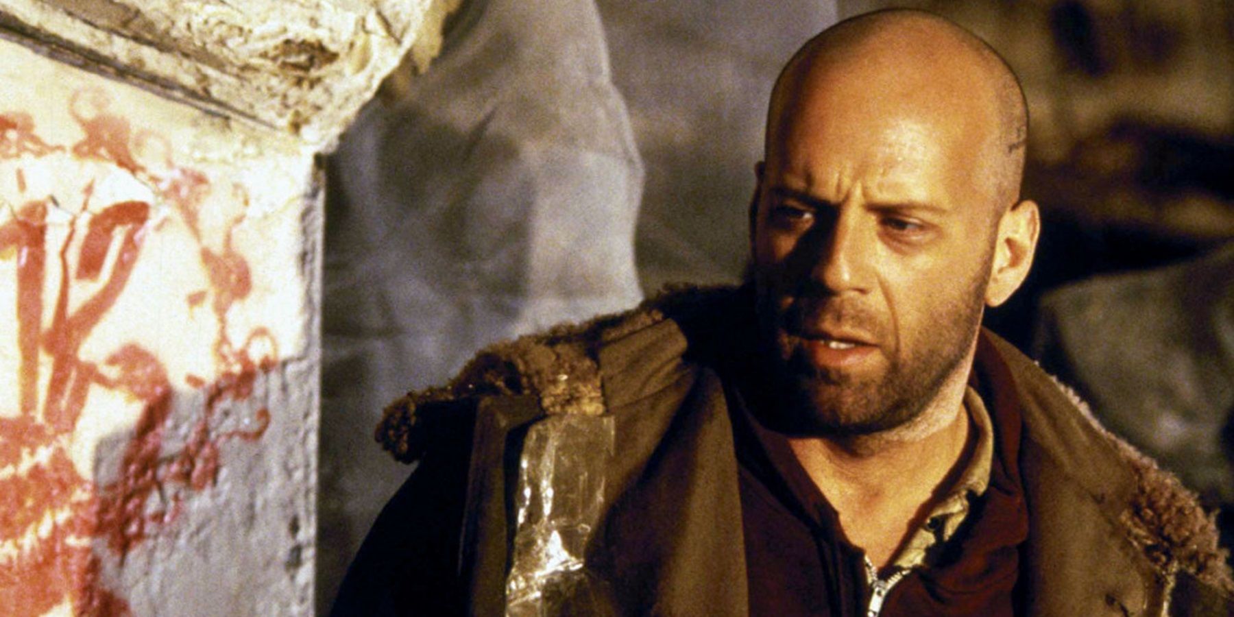 Bruce Willis olhando para uma marcação na parede em 12 Monkeys