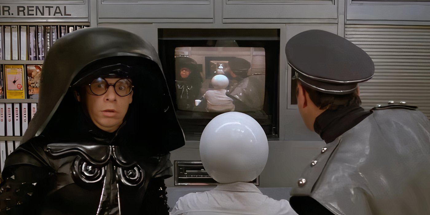 Darth Helmet looking into the camera in Spaceballs as two men look at a screen