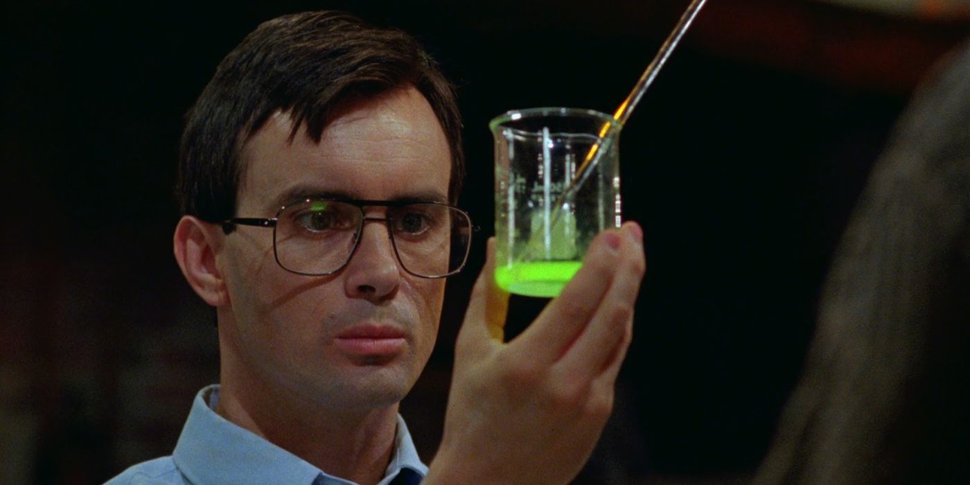 Dr. Herbert West (Jeffrey Combs) holding up a glowing green serum in Bride of Re-Animator.