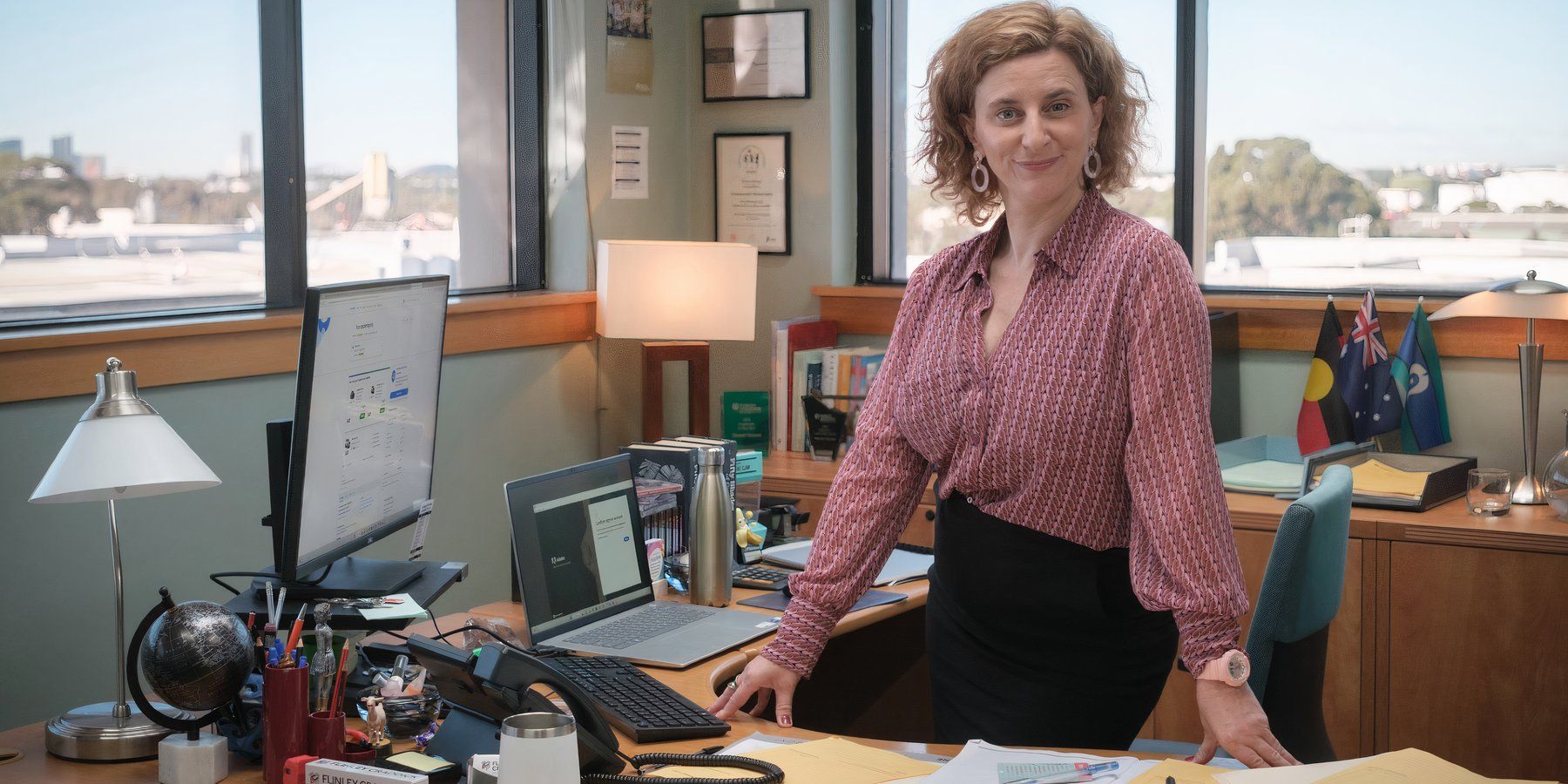 Felicity Ward as Hannah Howard sitting on a desk in Australian The Office remake-1