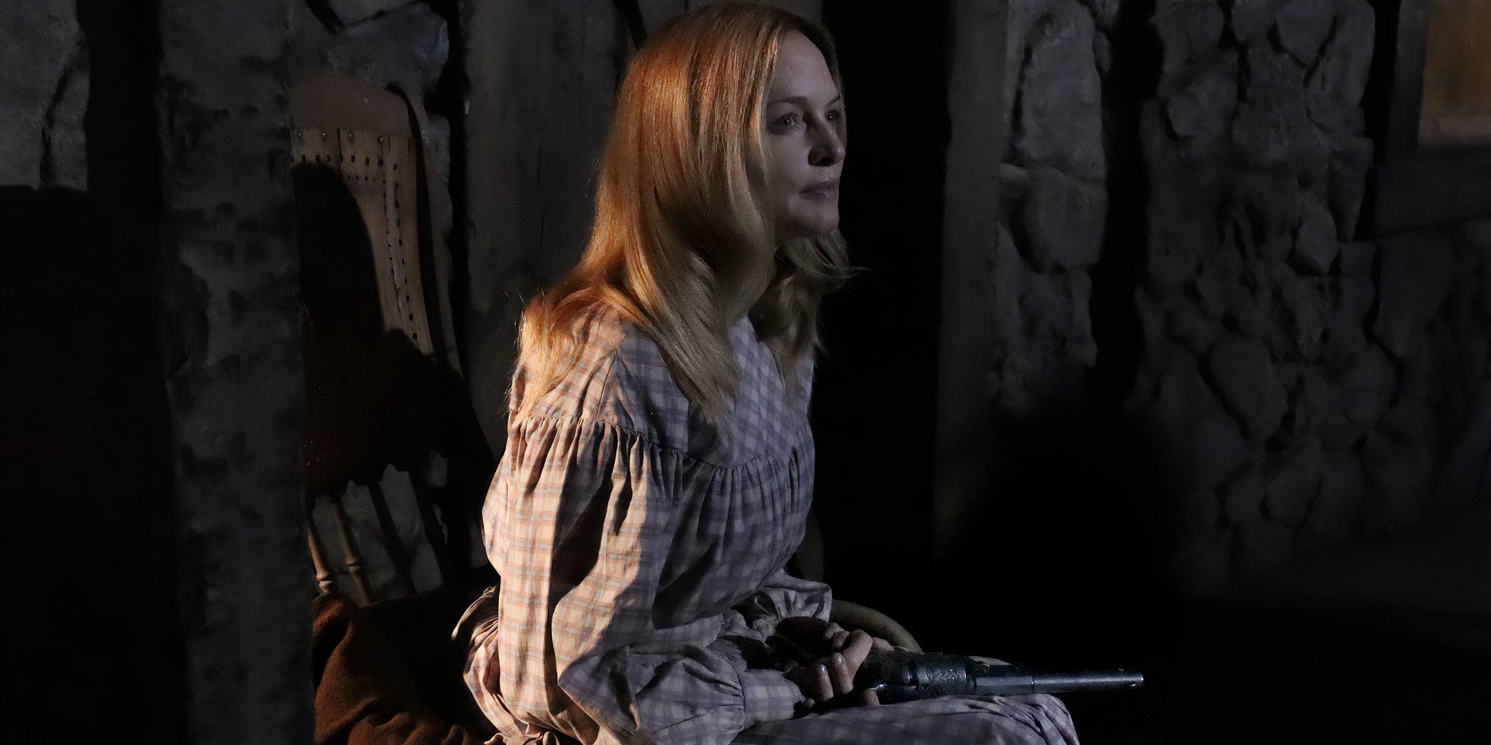 Heather Graham as Pandora, looking thoughtfully into the distance with a gun on her lap in Place of Bones