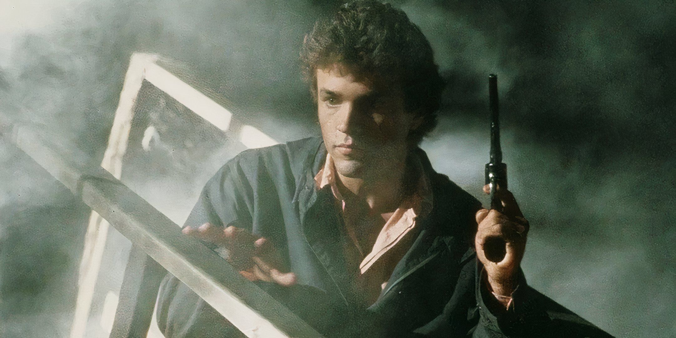 John J. York crouches behind a wooden rail and holds a gun up in the air. 