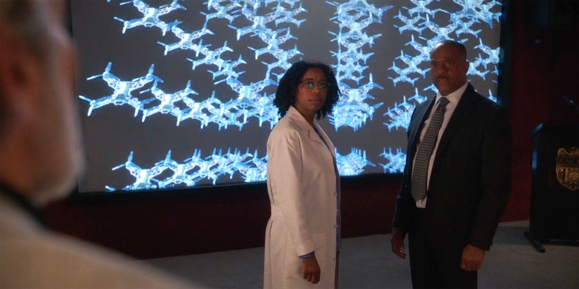 Kasie Hines and Leon Vance standing in front of a screen with dozens of drone models in NCIS season 21